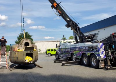 Sullivan's Towing & Recovery using a crane to lift an industrial part onto a flatbed