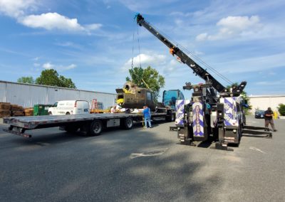 Sullivan's Towing & Recovery using a crane to lift an industrial part onto a flatbed