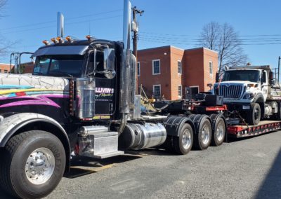 Sullivan's Towing & Recovery flatbed truck with a dump truck being towed