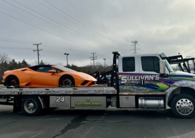 Sullivan's Towing & Recovery, LLC truck towing an orange sports car